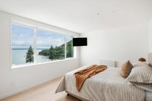 Un dormitorio con una cama y una ventana grande. en Panorama Penthouse Luxe Ocean Views & Pool, en Mount Maunganui