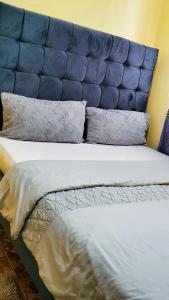 a large bed with a blue padded head board at Salash apartments in Nairobi +6 photos