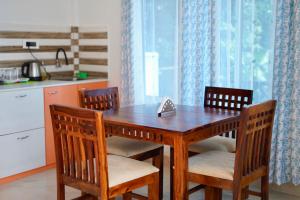 a wooden table with four chairs and a kitchen at Lakeland Homestay Diphu in Diphu