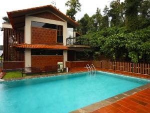 a swimming pool in front of a house at Villa Katipadu Coorg in Srimangala