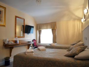 a hotel room with two beds and a desk and a window at Gatwick Cambridge Hotel in Horley