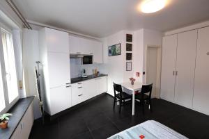 Una cocina con gabinetes blancos y una mesa con sillas. en Apartment near train station, en Luxemburgo 7 fotos más