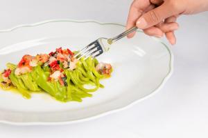 a person eating a plate of broccoli with shrimp on it at Rocco Forte The Charles Hotel in Munich