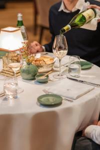 a person pouring wine into a glass on a table at Rocco Forte The Charles Hotel in Munich