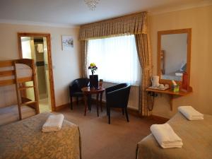 a room with two beds and a table and a window at Gatwick Cambridge Hotel in Horley