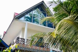 a house with a palm tree in front of it at Lakeland Homestay Diphu in Diphu