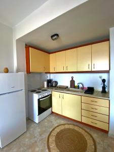 a kitchen with wooden cabinets and a white refrigerator at Vaso Apartment in Neos Marmaras