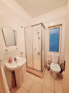 ein Badezimmer mit Dusche, Toilette und Waschbecken in der Unterkunft Mountain Seaview Penthouse in a Holiday Village 10 in Ayios Yeoryios