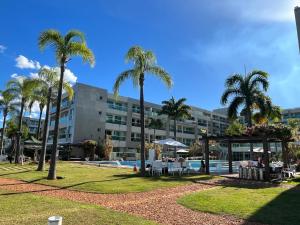 a hotel with palm trees in front of a pool at Flat na Beira do Lago in Brasilia