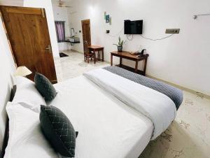 a bedroom with two white beds and a television at White Home Stay in Kanyakumari
