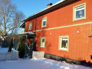 una casa rossa con la neve davanti di Ateljé Vävglädje Butik Bed & Breakfast a Sunnansjö