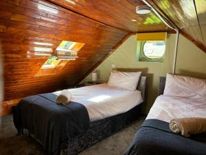 two beds in a room with a wooden ceiling at The Annexe at Gomo in East Winch