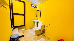 a yellow bathroom with a toilet and a sink at Sameer beachfront Cottages in Canacona