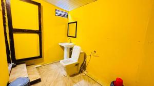 a yellow bathroom with a sink and a toilet at Sameer beachfront Cottages in Canacona