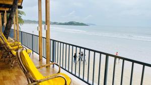 two people standing on a balcony looking at the beach at Sameer beachfront Cottages in Canacona