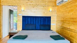 a bed in a wooden room with two towels on it at Sameer beachfront Cottages in Canacona