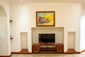 a living room with a tv and a painting on the wall at Family 3bed House in Kampala