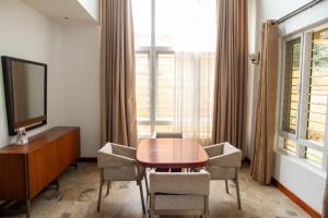 a room with a table and chairs and a television at Family 3bed House in Kampala