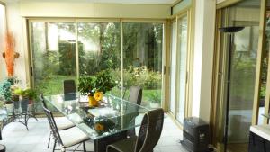 une table et des chaises en verre dans une chambre avec fenêtre dans l'établissement Plein Soleil, à Mandelieu-la-Napoule