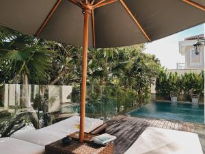 a table with an umbrella next to a swimming pool at Kula Kara Villas Bingin, Uluwatu in Uluwatu