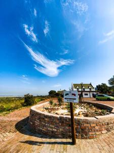 a sign in front of a brick wall with a house at Capelands Resort, Italian Restaurant & Winery in Cape Town
