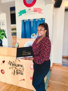 a young woman standing next to a table holding a box at Capelands Resort, Italian Restaurant & Winery in Cape Town