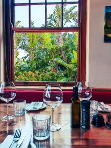a wooden table with wine glasses and a window at Capelands Resort, Italian Restaurant & Winery in Cape Town