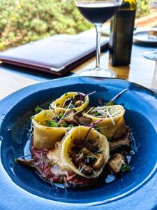 a blue plate of food on a table with a glass of wine at Capelands Resort, Italian Restaurant & Winery in Cape Town