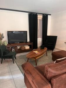 a living room with couches and a flat screen tv at La Petite Maison in Montbard