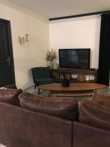 a living room with a couch and a tv at La Petite Maison in Montbard