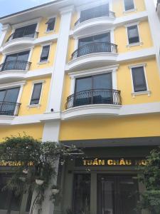 a tall yellow building with a sign for a hair salon at Tuần Châu HQT in Ha Long