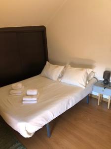 a bed with white sheets and pillows on it at Casa da Tia Balbina - Medeiros in Medeiros +1 photo
