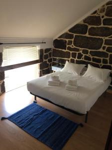a bed in a room with a stone wall at Casa da Tia Balbina - Medeiros in Medeiros