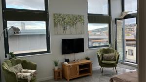 a living room with two chairs and a flat screen tv at SWANSEA BAY, MARINA & ARENA VIEW Mins to BEACH & CITY in Swansea
