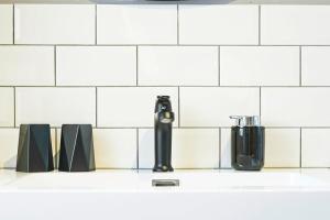 a white tiled kitchen with a counter top with a bottle and cups at Apartment Afitojen in Postira +18 photos