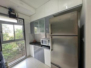 a kitchen with a stainless steel refrigerator and a window at Residential Tranquil in Mumbai