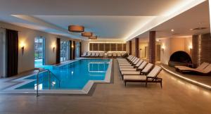 巴特欣德朗Alpin Lodges - Moderne Appartements mit Zugang zu 3000 qm SPA Panoramahotel Oberjoch的一个带躺椅的酒店游泳池