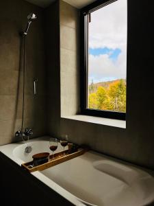 a bathroom with a bath tub with two glasses of wine at Mountain Nest in Silver Mountain Poiana Brasov in Poiana Brasov