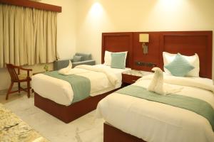 克久拉霍Hotel Scala的有两张床和一把椅子的酒店房间
