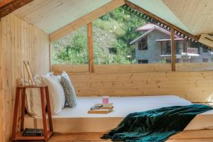 a bed in a wooden room with a large window at SaffronStays Fairytale Villa - 3 bedroom villa in orchards and access to the river in Gushaini