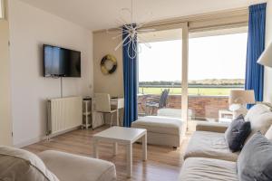 ein Wohnzimmer mit Sofa und Fernseher in der Unterkunft Duinerei appartement C102 in Callantsoog