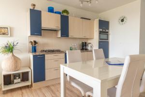 eine Küche mit einem weißen Tisch und blauen Schränken in der Unterkunft Duinerei appartement C102 in Callantsoog