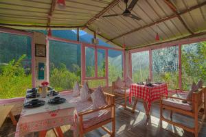 a dining room with a table and chairs and windows at SaffronStays Fairytale Villa - 3 bedroom villa in orchards and access to the river in Gushaini
