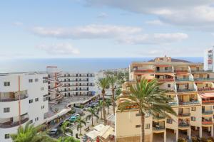 a view of a city with palm trees and buildings at LUXORY DREAMY SUNSET, SeaFront, Direct Access To The Promenade,Wifi,Pool,Free Parking in Los Cristianos