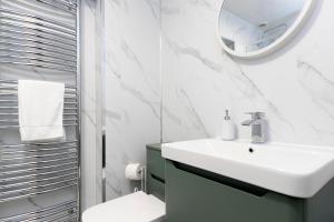 a white bathroom with a sink and a mirror at Ferndene House in Darlington