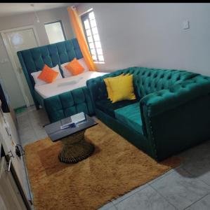 een woonkamer met een groene bank en een tafel bij Jessy stays in Nairobi