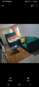 een woonkamer met een groene bank en een tafel bij Jessy stays in Nairobi