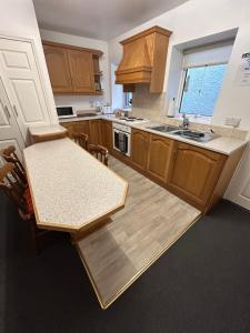 eine Küche mit Holzschränken, einem Tisch und einer Spüle in der Unterkunft Central Town House,Moville 61 in Moville