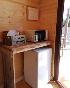 a kitchen with a counter with a microwave and a refrigerator at Camping Playa Mazagón in Mazagón +38 photos