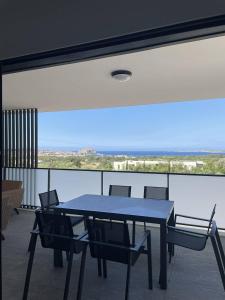 a blue table and chairs in a room with a large window at Appartement avec vue panoramique sur la mer in Calvi